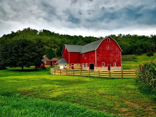 a red barn surrounded by a wooden gate on a farm